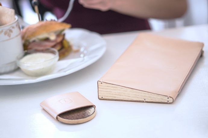 Dřevěné kožené psaníčko Lux Clutch a dřevěné zrcátko Liti položené v restauraci na stole