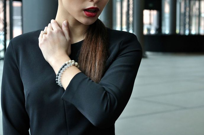 Žena v černých šatech na rukou má unikátní náramky s dřevěným detailem